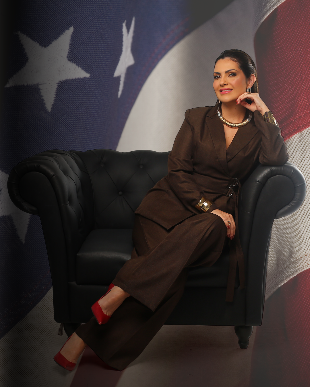 Anacélia Santiago, paralegal especializada em EB-2 NIW, sentada em uma poltrona de couro com a bandeira dos Estados Unidos ao fundo